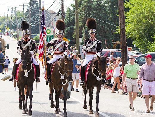 Men in uniforms riding horses in fourth of July parade